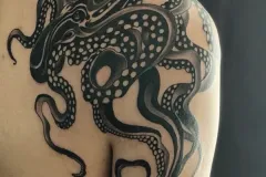 Un primer plano del hombro y la parte alta del brazo con un tatuaje grande y detallado de pulpo en blackwork. El diseño muestra tentáculos negros y expresivos, que fluyen con fuerza, con ventosas en espacio negativo muy intrincadas que se envuelven de forma dinámica alrededor del deltoide. Tatuaje blackwork por Agu en Hipno Tattoo Estepona.