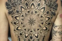 Tatuaje blackwork en espalda completa con mandala central simétrico, florales, patrones geométricos y dotwork. Tatuaje blackwork por Agu en Hipno Tattoo Estepona.